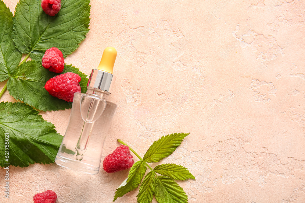 Bottle of cosmetic raspberry oil on pink table