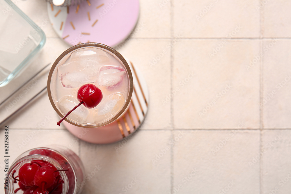 Glass of tasty cocktail with maraschino cherries on white tile background