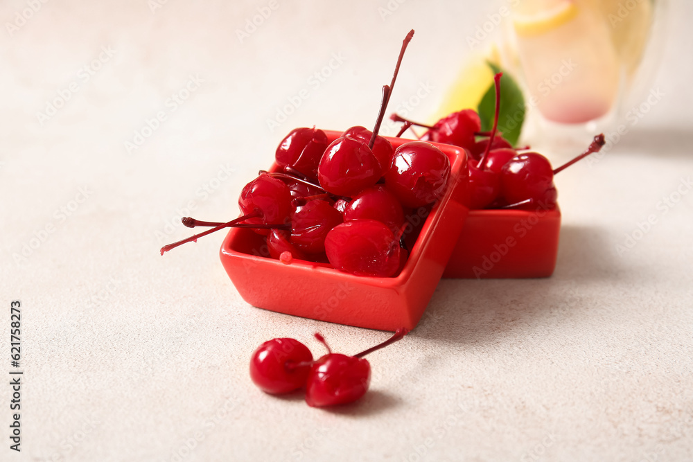 Bowls of tasty maraschino cherries on light background