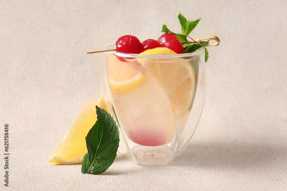 Glass of tasty cocktail with maraschino cherries on light background