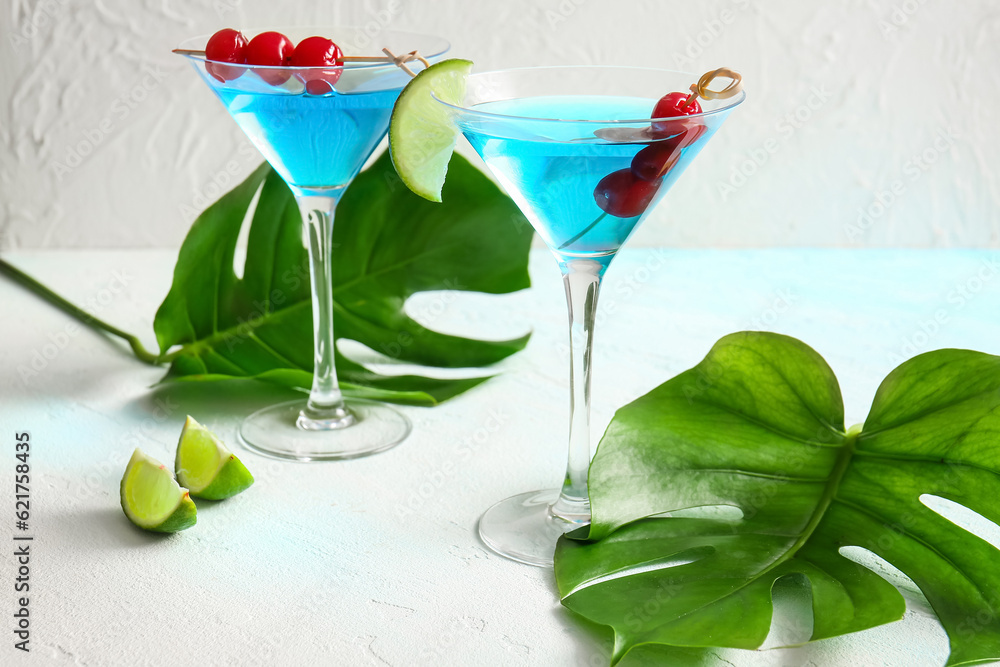 Glasses of tasty cocktail with maraschino cherries on light background