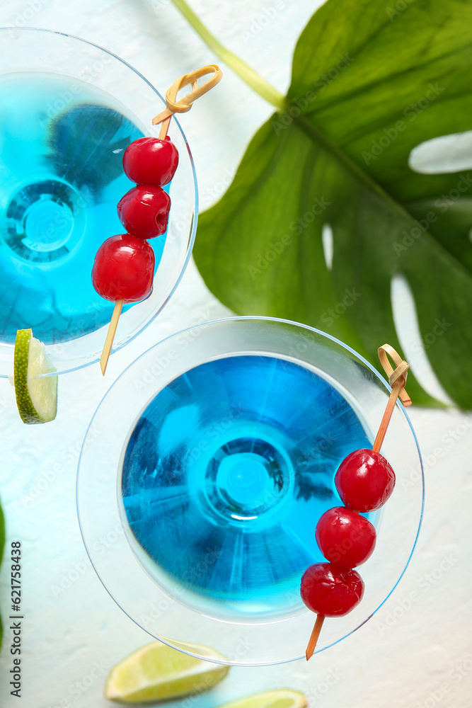 Glasses of tasty cocktail with maraschino cherries on light background