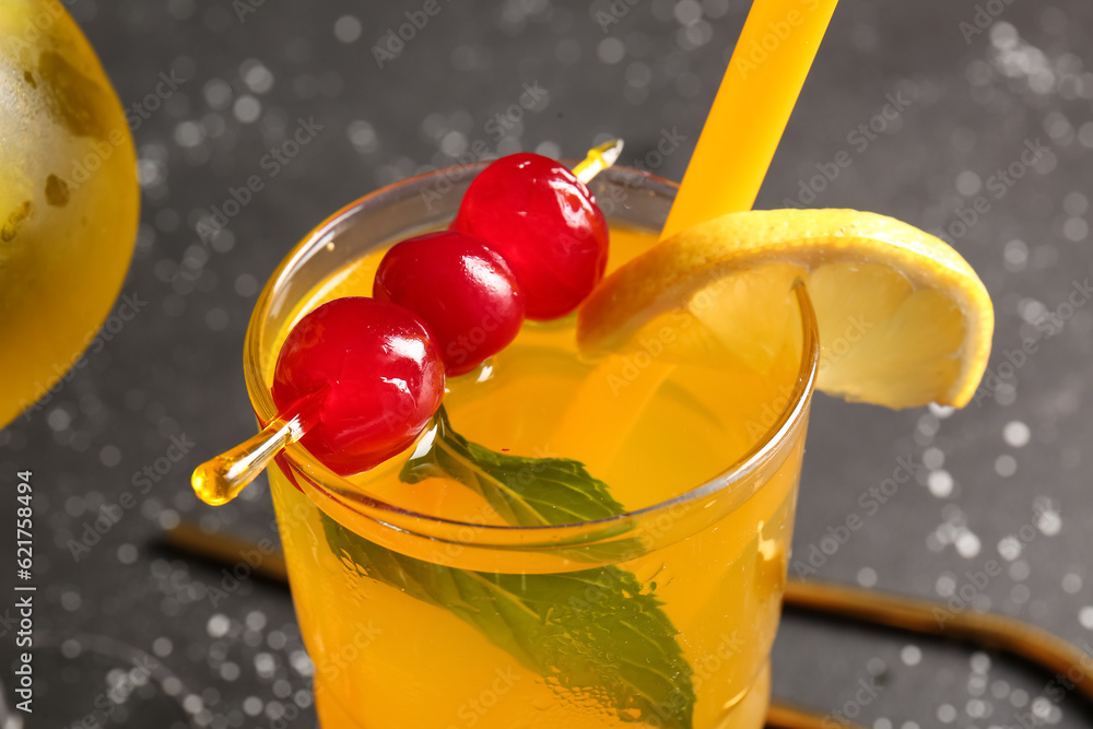 Glass of tasty cocktail with maraschino cherries on grey background