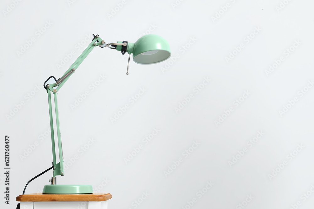 Modern lamp on table against light background