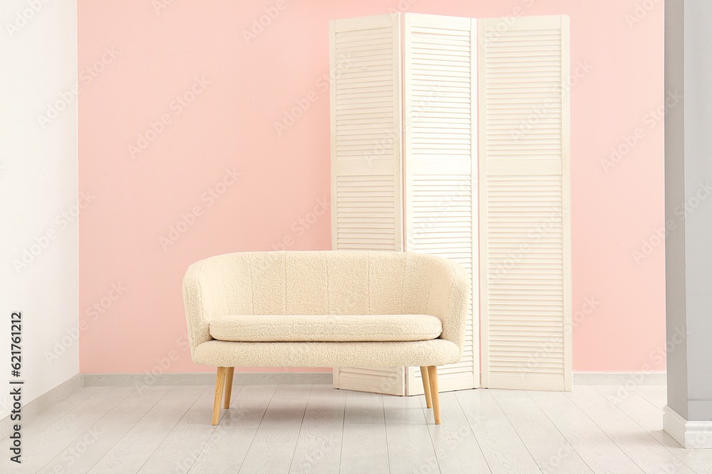 Folding screen and white sofa near pink wall