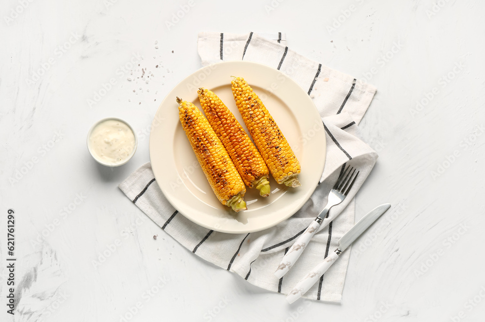 Plate with tasty grilled corn cobs and sauce on white background