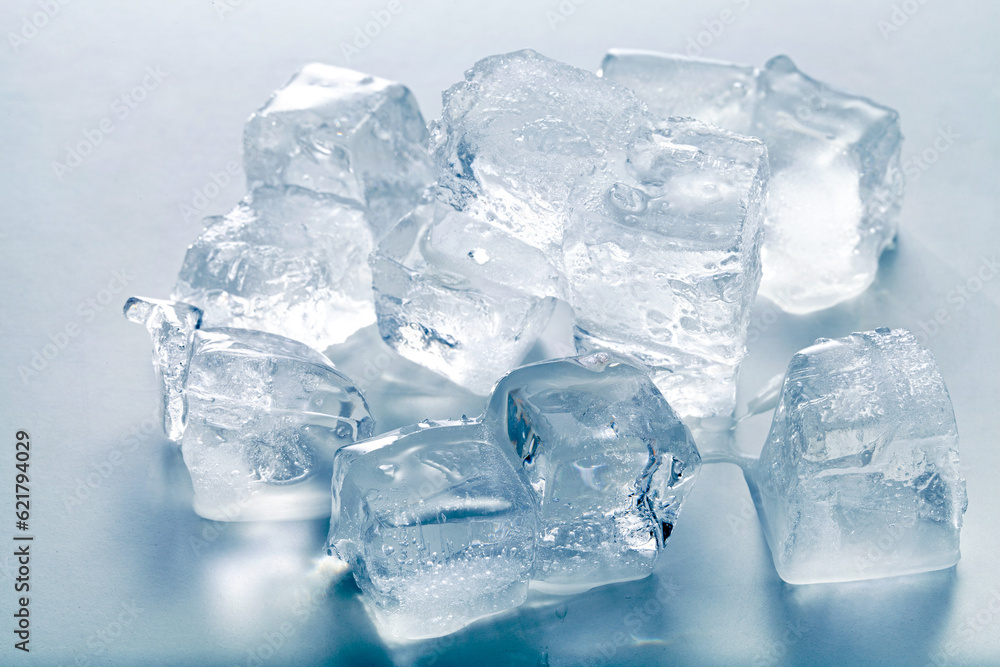 melting ice cubes with water drops on blue background.