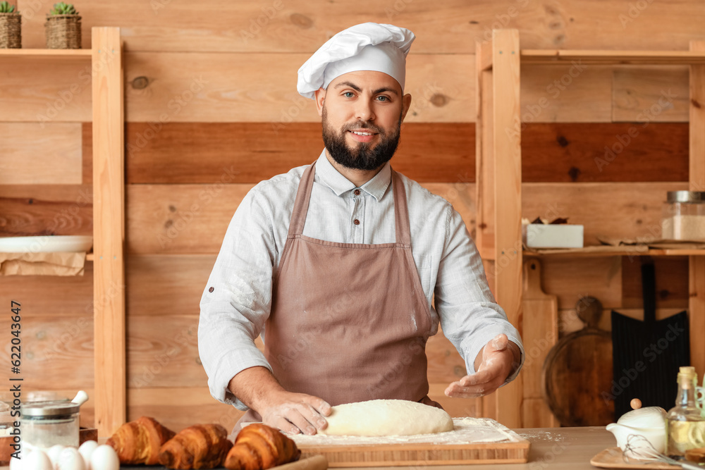 Male baker preparing dough for bread at table in kitchen