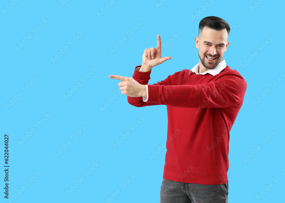 Handsome man showing loser gesture on blue background