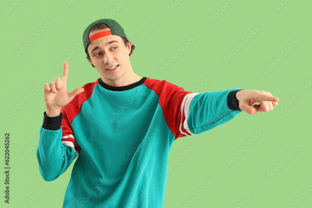 Young man showing loser gesture on green background