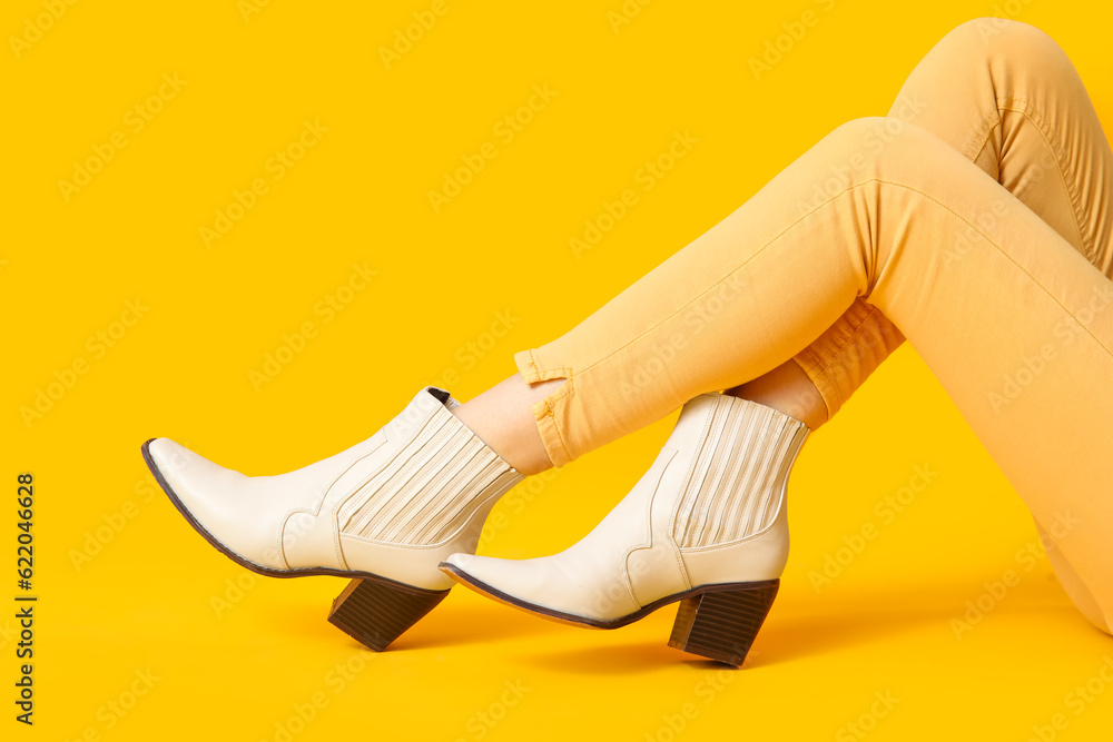 Female legs in stylish shoes on yellow background