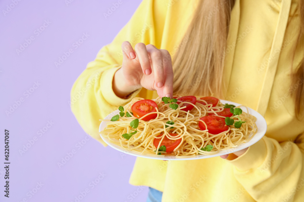 Young woman with tasty pasta on lilac background, closeup