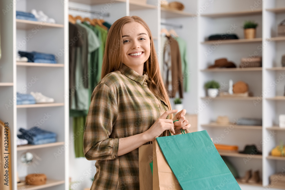 Happy young woman with shopping bags in boutique