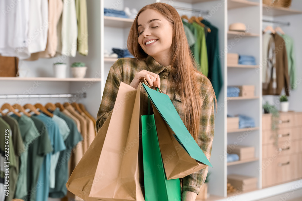 Happy young woman with shopping bags in boutique