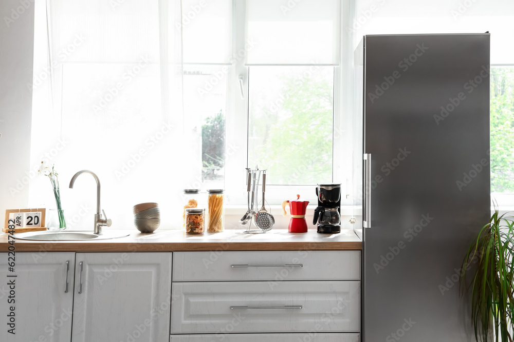 Interior of kitchen with stylish fridge, counters and window