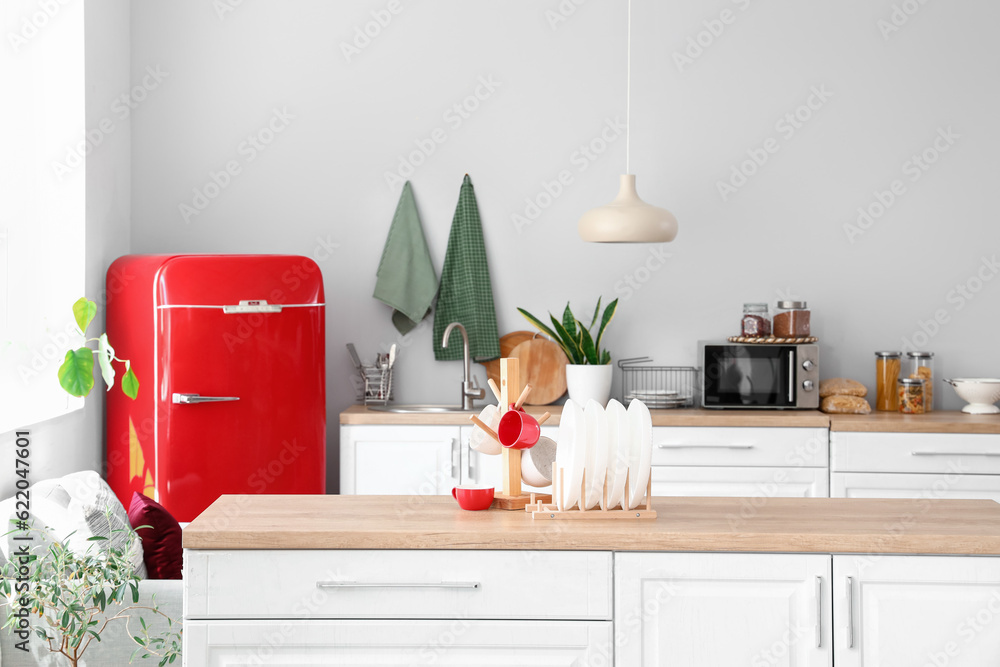 Interior of light kitchen with red fridge and counters