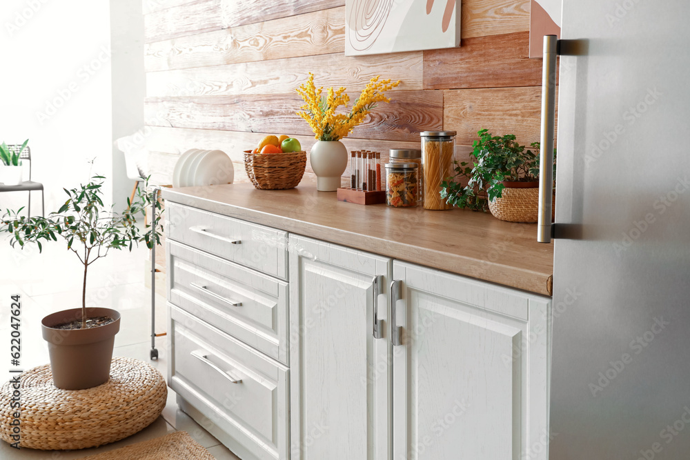 Interior of kitchen with stylish fridge, counters and houseplant