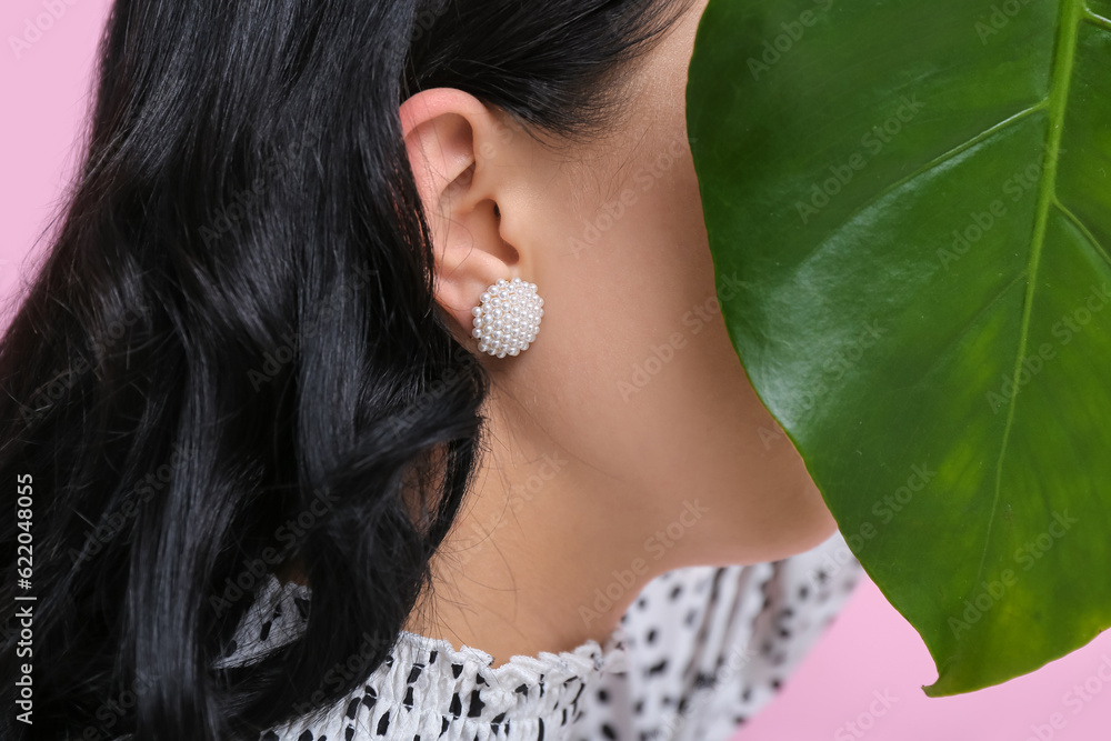 Profile of beautiful young woman wearing stylish earrings near pink wall