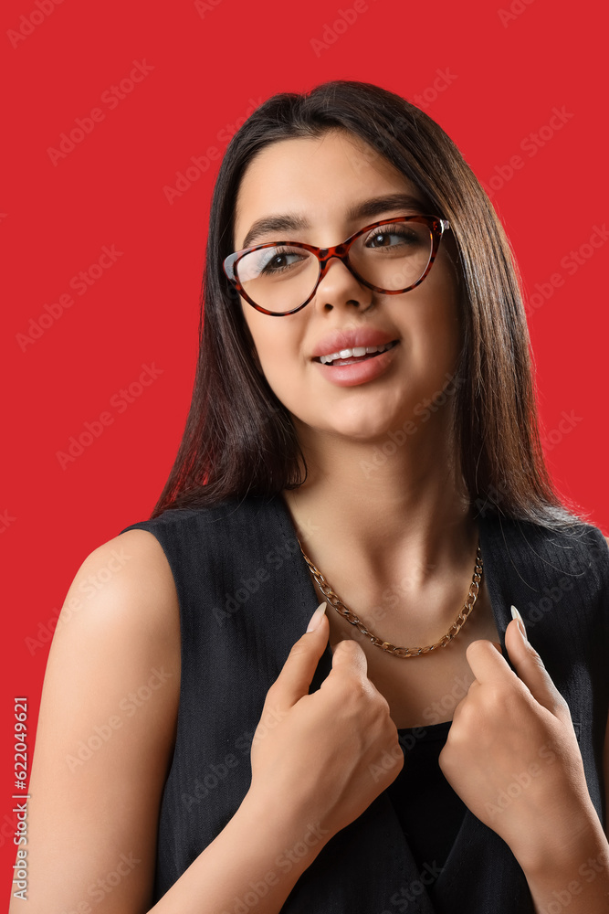 Fashionable young woman wearing glasses on red background