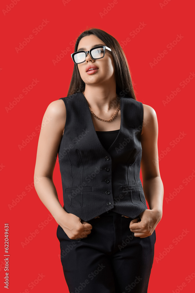 Fashionable young woman wearing glasses on red background