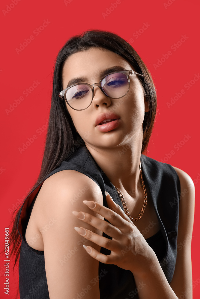 Fashionable young woman wearing glasses on red background