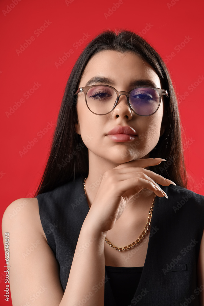 Fashionable young woman wearing glasses on red background