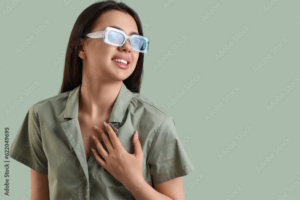 Beautiful young woman wearing stylish  sunglasses on color background