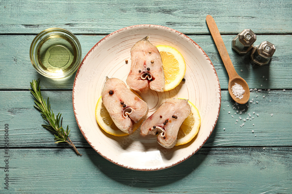 Pieces of raw codfish with lemon on green wooden background