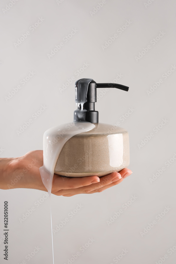 Hand with liquid soap on grey background