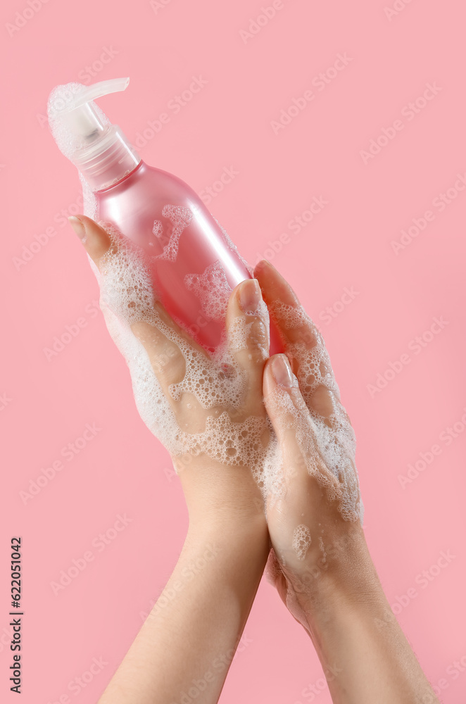 Hands with liquid soap on pink background