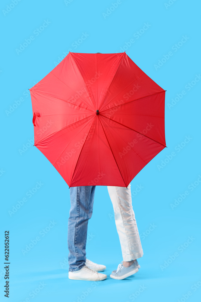 Young couple with umbrella on blue background