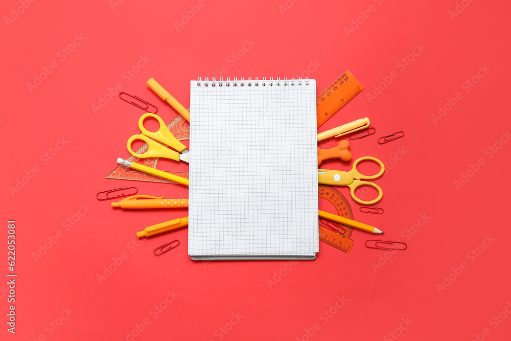 Composition with blank notebook and school stationery on red background