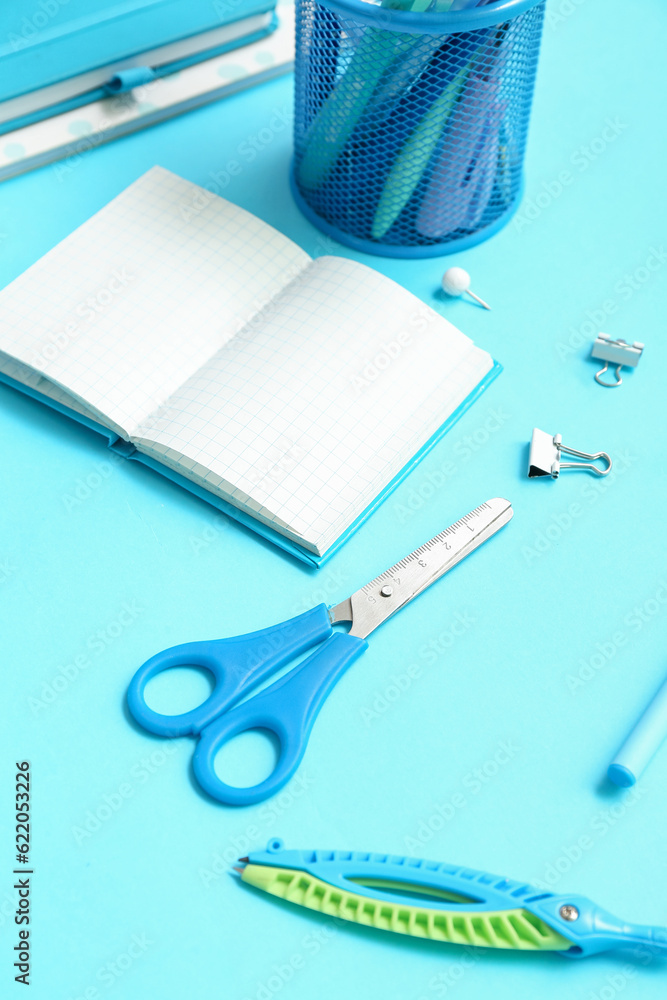 Notebook with school stationery on blue background, closeup