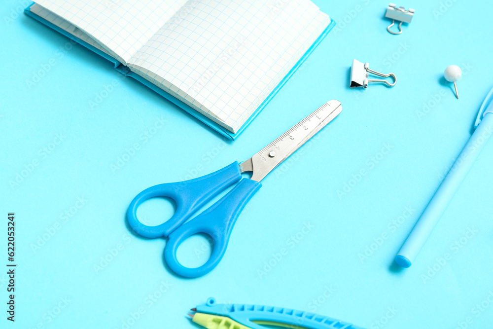 Notebook with school stationery on blue background, closeup