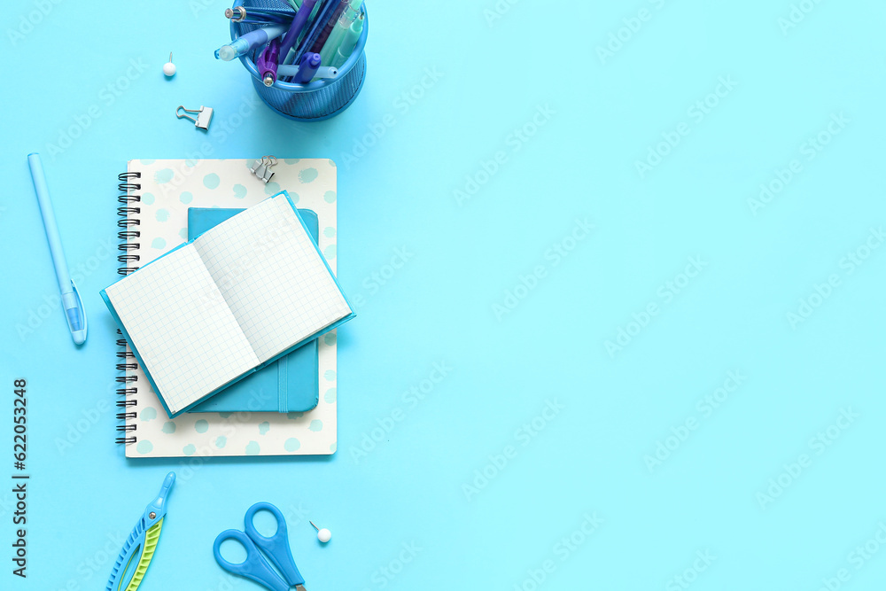 Composition with notebooks and different school stationery on blue background