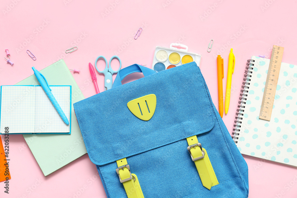 School backpack with different stationery on pink background