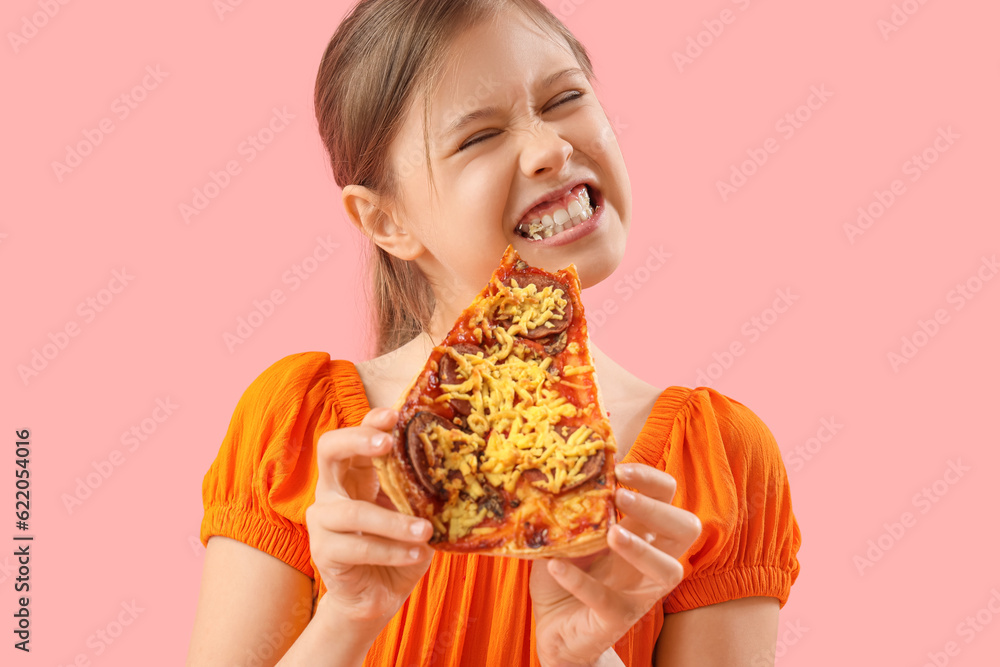 Angry little girl eating tasty pizza on pink background, closeup