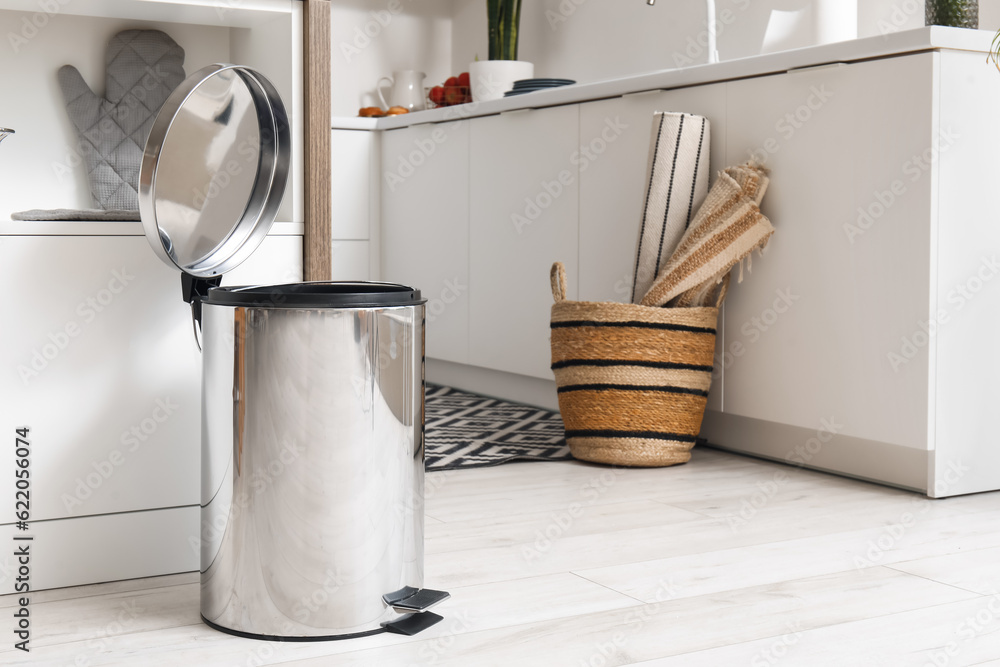 Opened metallic trash bin near table in interior of modern kitchen