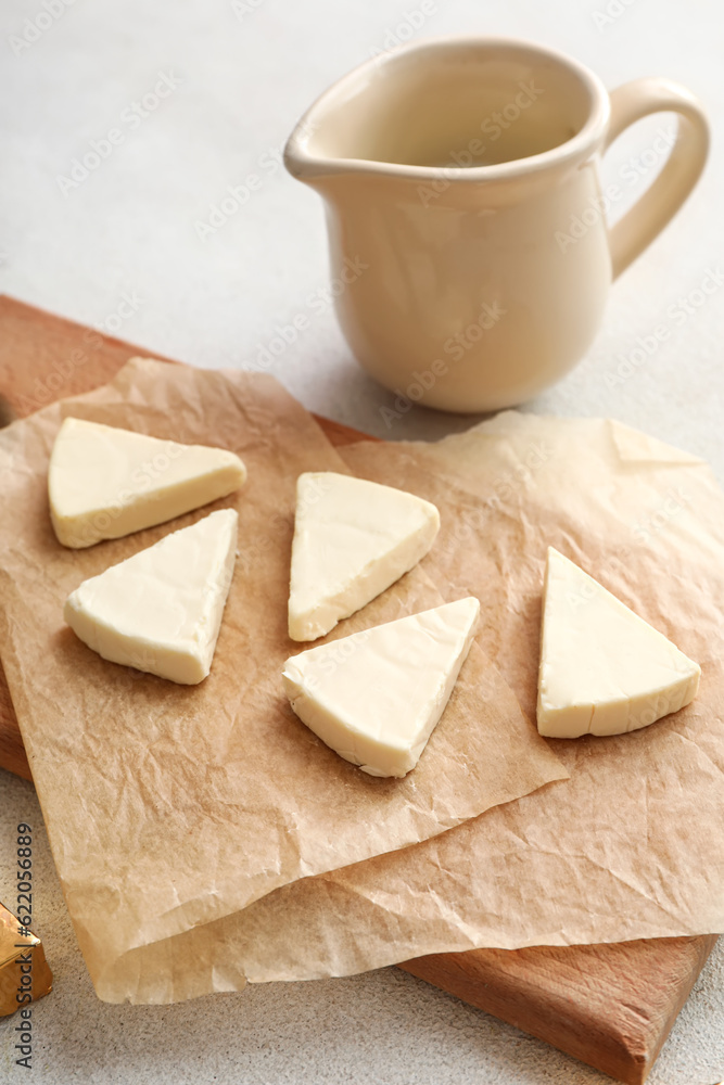 Board with triangles of tasty processed cheese on light background, closeup