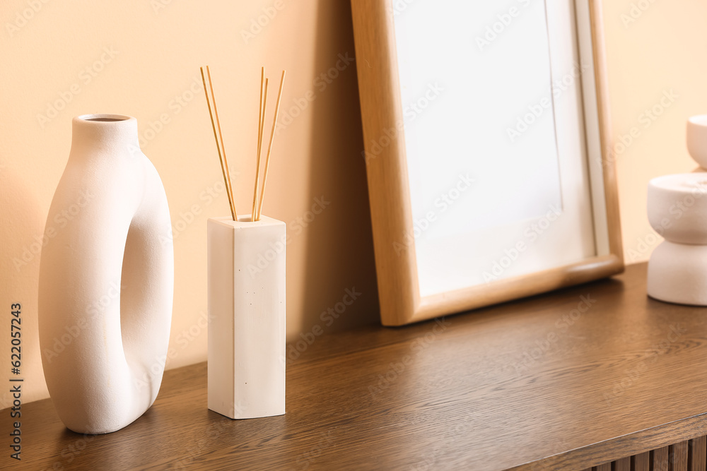 Bottle of reed diffuser on table near beige wall in room, closeup