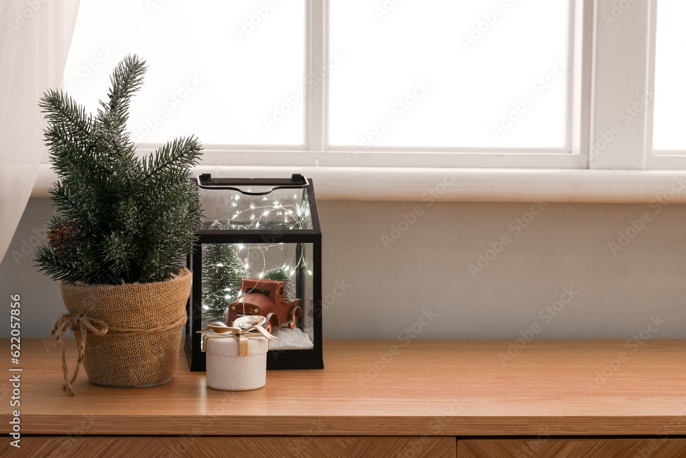 Small fir tree, gift box and Christmas decor on table near window, closeup