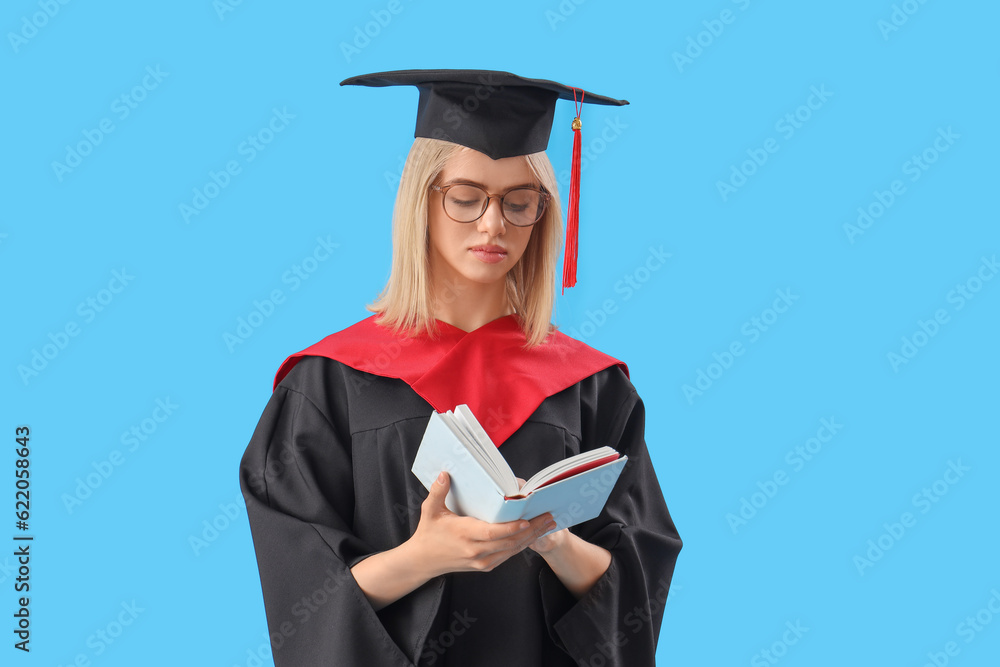 Female graduate student reading book on blue background