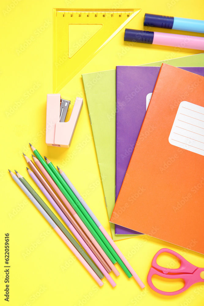 Notebooks with different stationery on yellow background