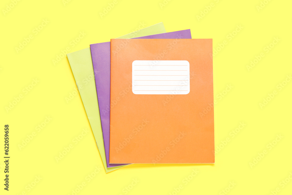 Different colorful notebooks on yellow background