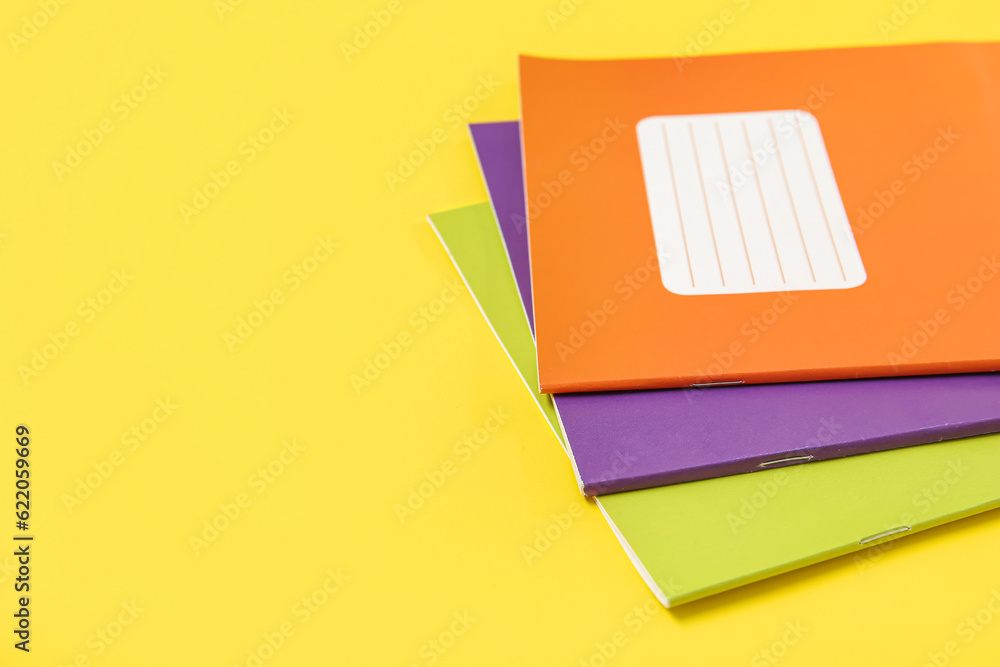 Different colorful notebooks on yellow background