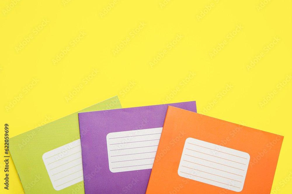 Different colorful notebooks on yellow background