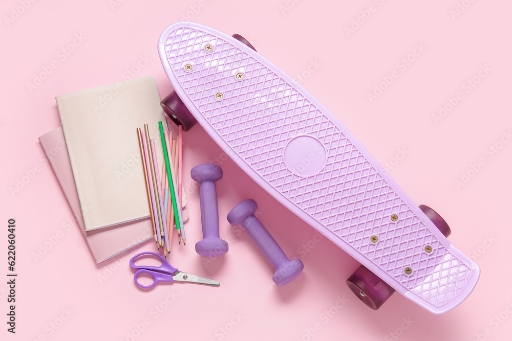 Skateboard with dumbbells and different stationery on pink background