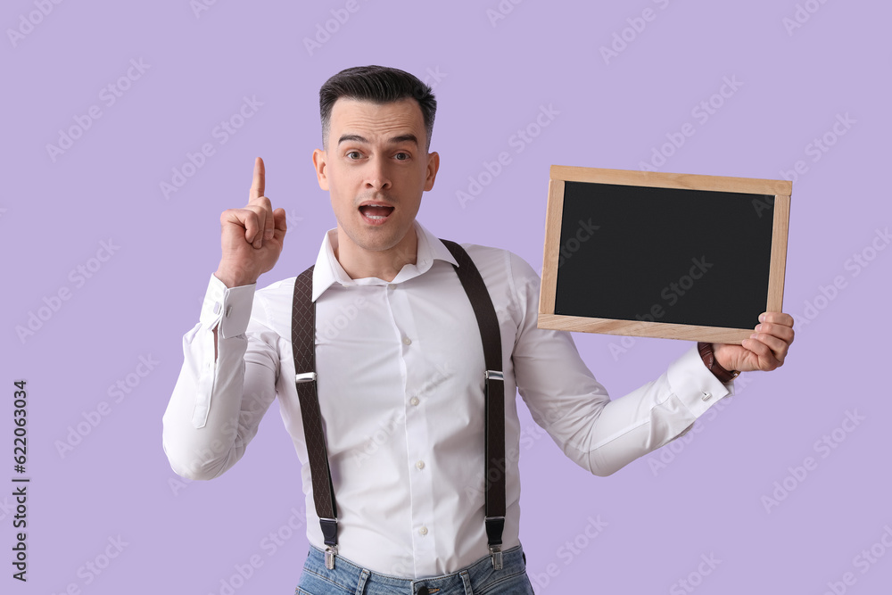 Male teacher with chalkboard pointing at something on lilac background