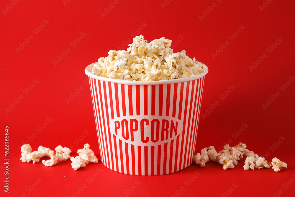 Bucket with tasty popcorn on red background