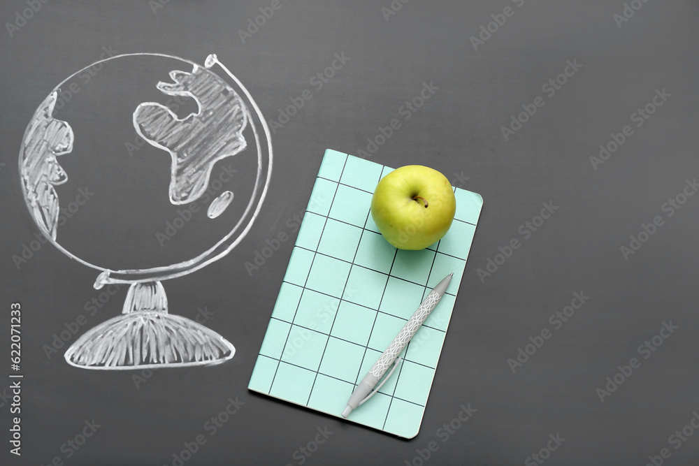 Stationery with fresh apple and drawn globe on black chalkboard